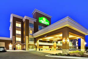 Um hotel La Quinta Inn & Suites com uma entrada bem iluminada, área de estacionamento e vista clara da fachada do edifício.