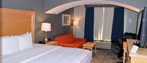 Een hotelkamer met een groot bed, een bureau, een stoel en een bank.