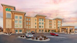 A hotel with a modern design, featuring a prominent sign, multiple floors, and a parking lot with several cars. - La Quinta Inn & Suites by Wyndham Paducah (Paducah)