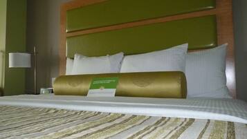 Una habitación de hotel con una cama bien hecha, un cabecero verde y una lámpara de noche.