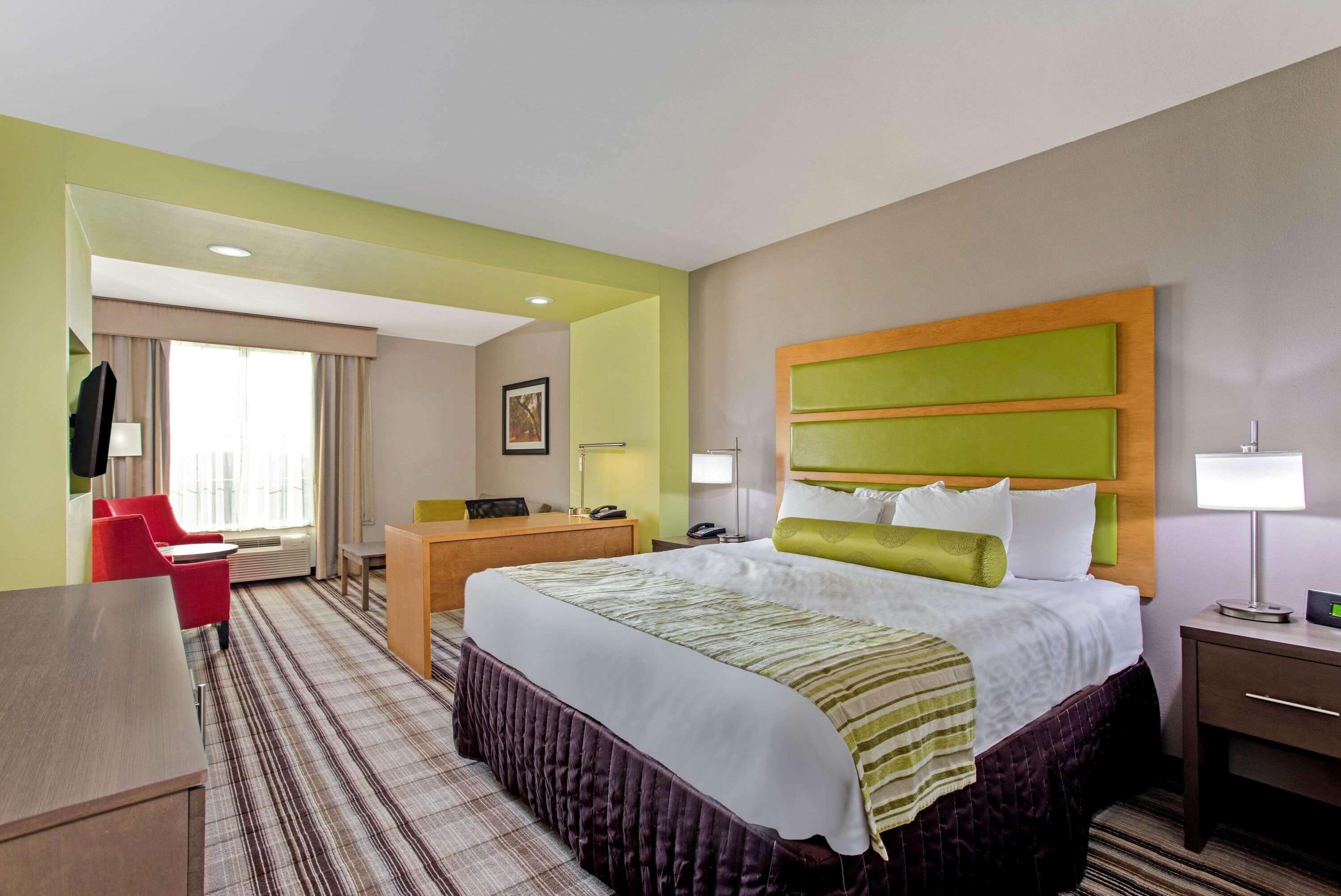 A hotel room with a large bed, a desk, a chair, and a TV.