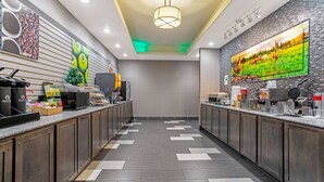 A modern hotel lobby with a long reception desk, a large digital screen displaying a scenic image, and a patterned floor design. - La Quinta Inn & Suites by Wyndham Paducah (Paducah)