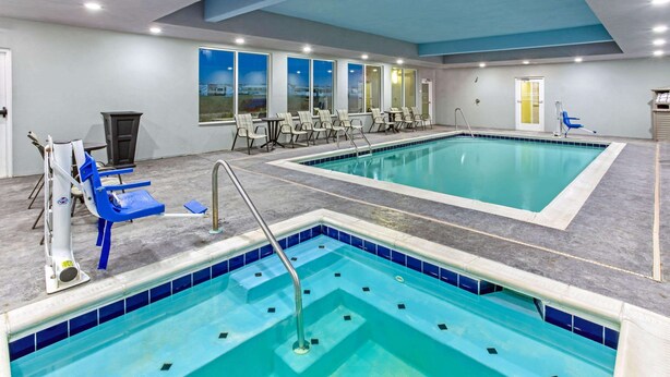 A swimming pool with multiple lanes, lounge chairs, and a view of the outdoors through large windows. - La Quinta Inn & Suites by Wyndham Paducah (Paducah)