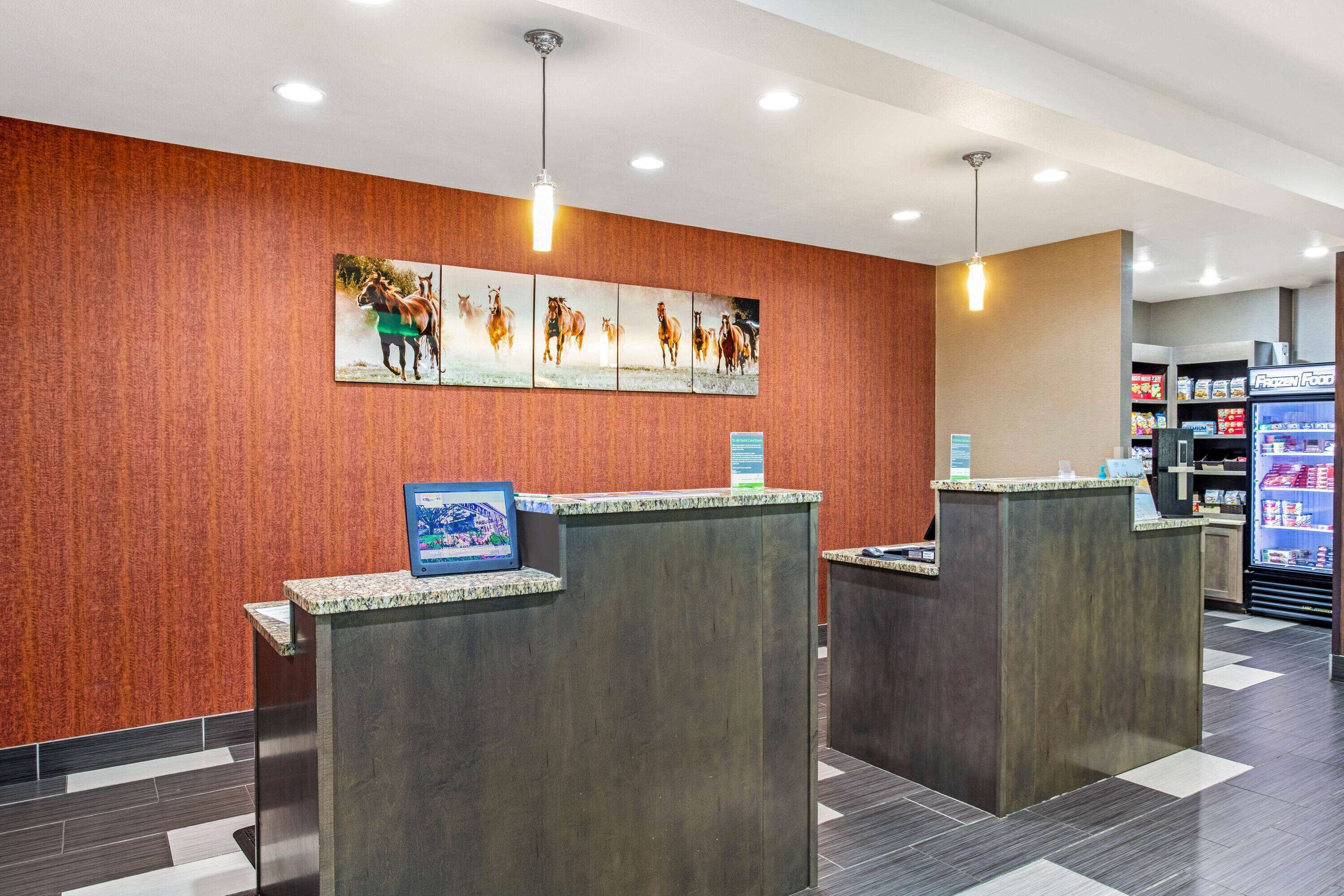 A reception area with two counters, a wall-mounted horse painting, and a vending machine in the background.