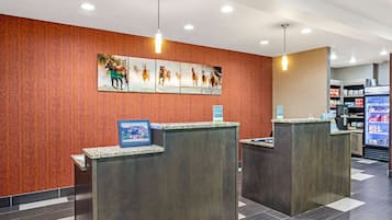 A reception area with two counters, a wall-mounted horse painting, and a vending machine in the background.