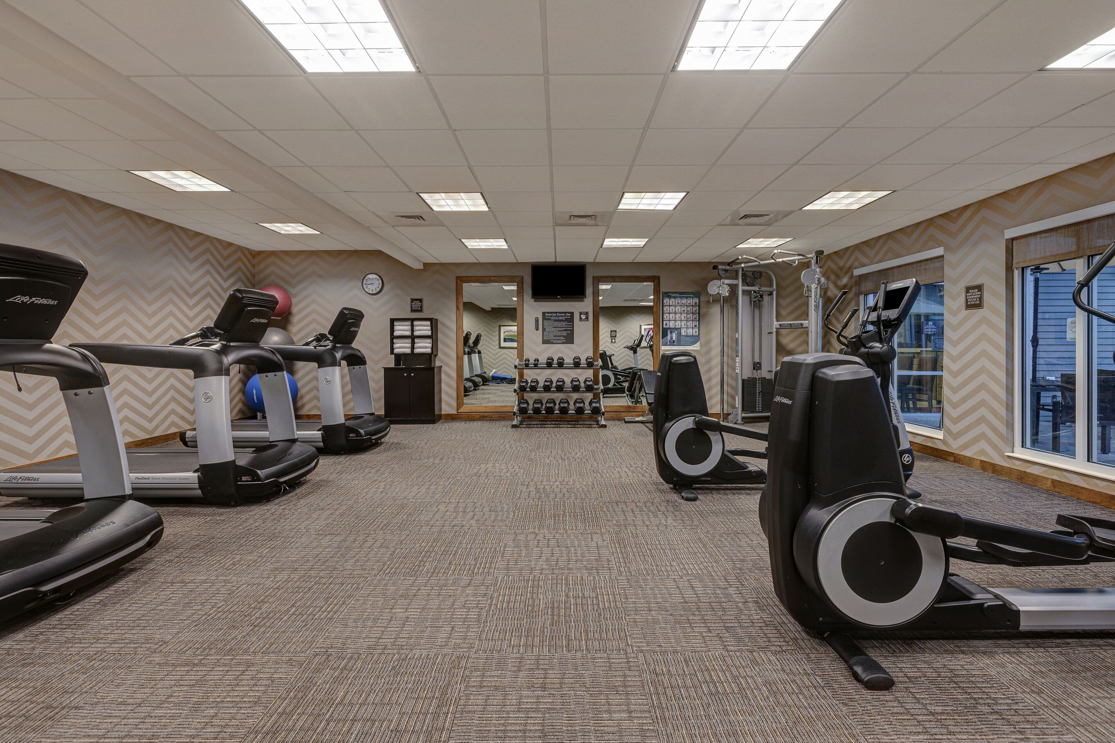A gym with treadmills, elliptical machines, and weight machines.