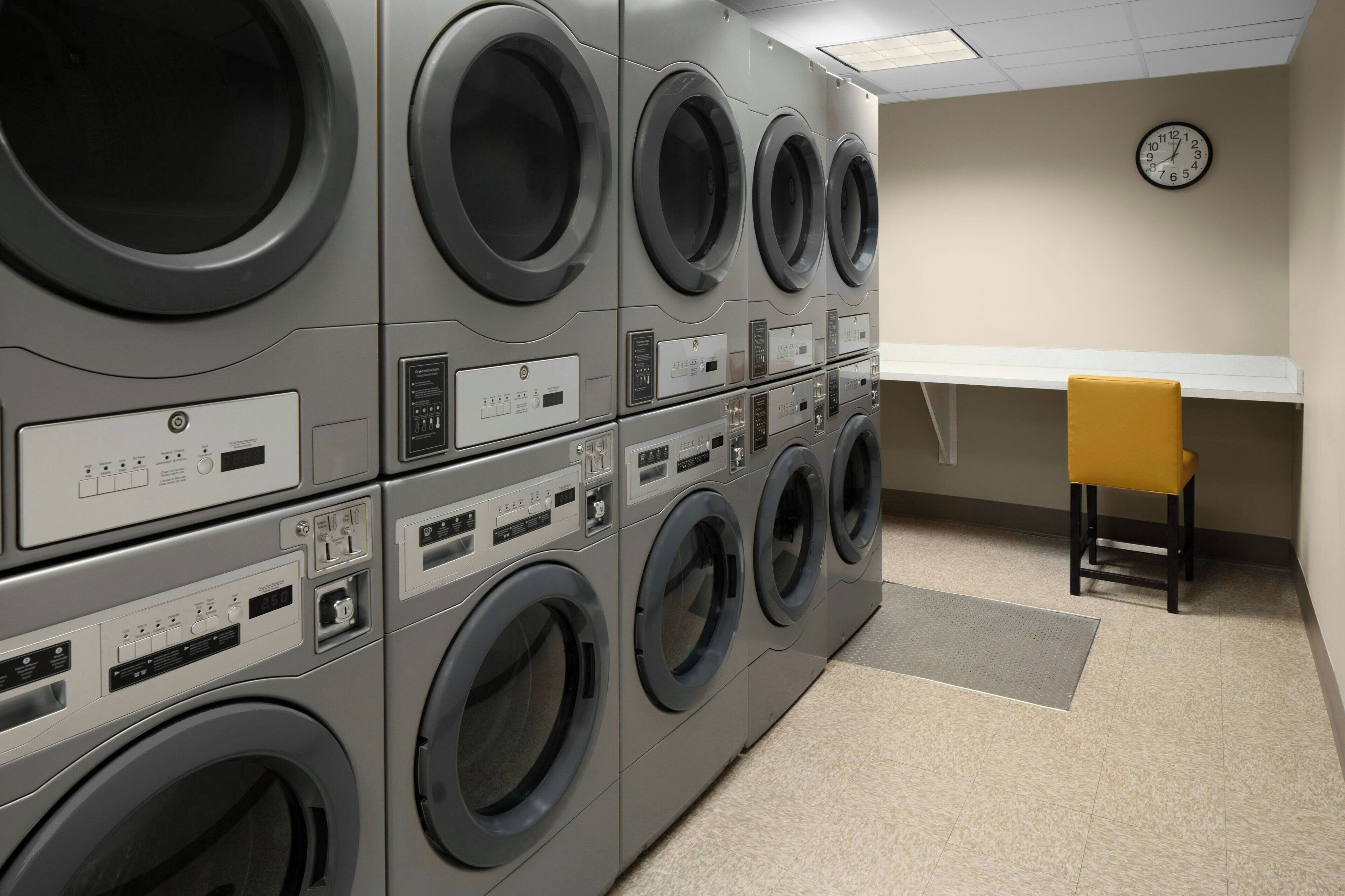 A laundry room with multiple washing machines and a chair.
