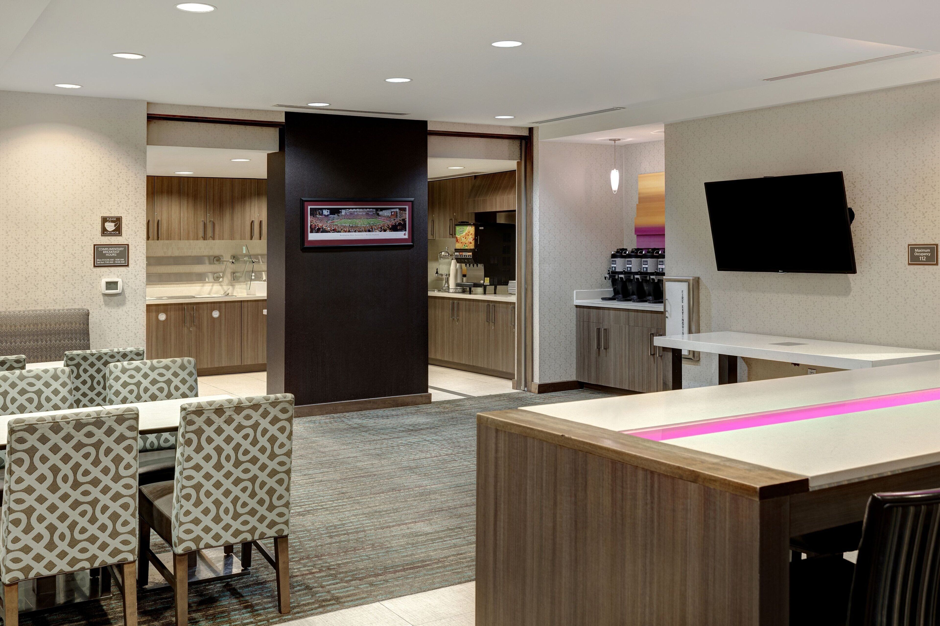 A hotel lobby with a reception desk, seating area, and a television mounted on the wall.