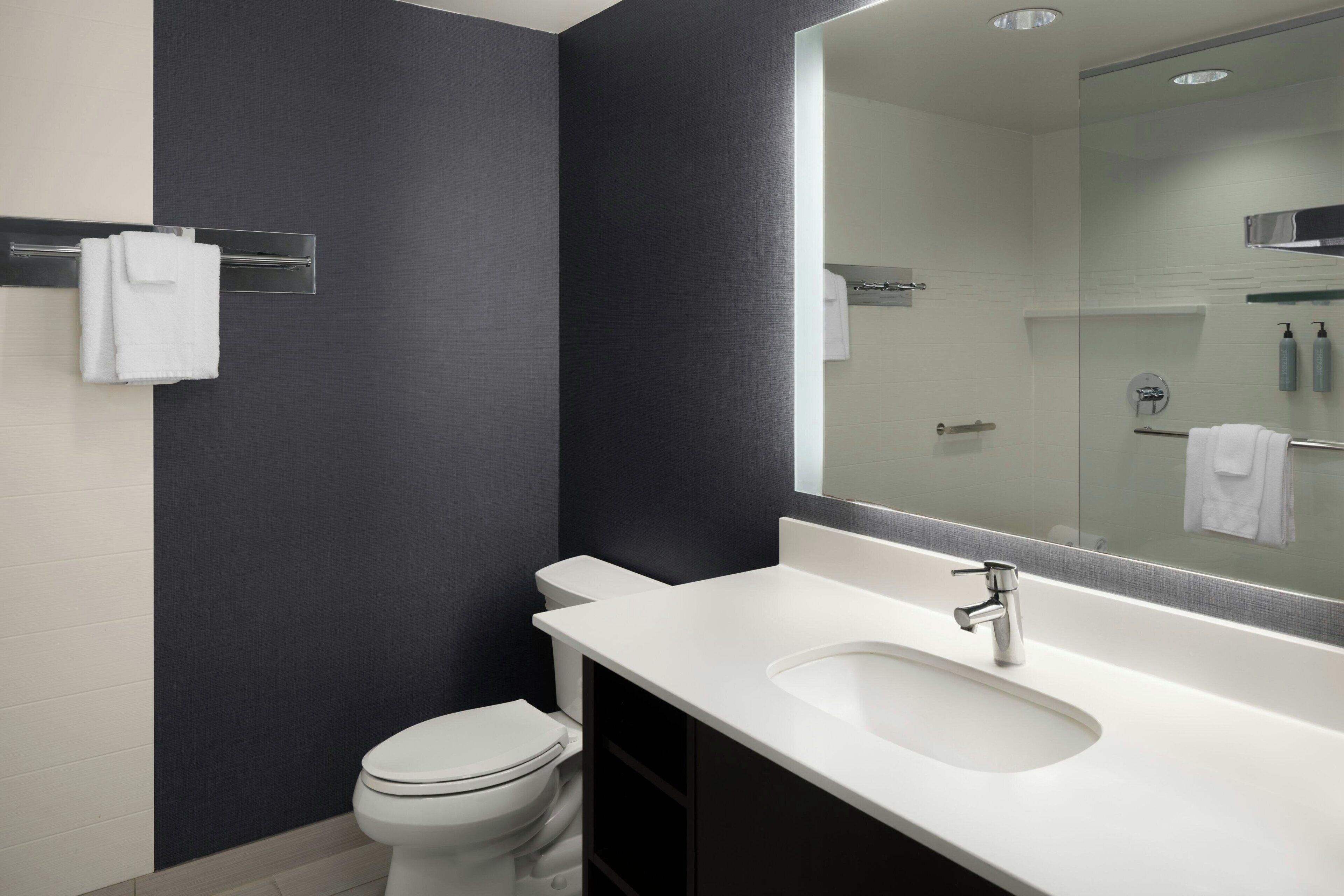 Un baño moderno con un lavamanos blanco, un espejo grande y un inodoro.