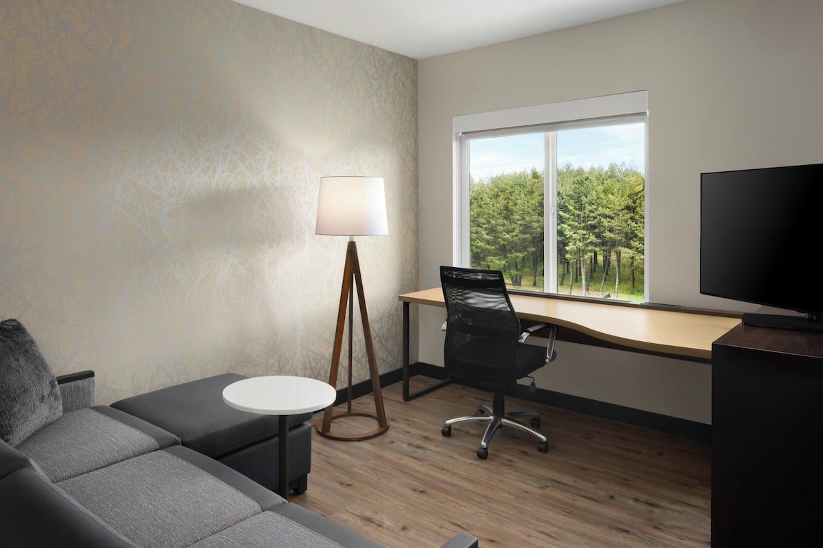 A modern room with a sofa, a desk, a lamp, and a TV.