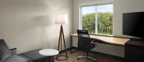 Ett modernt rum med en soffa, ett skrivbord, en lampa och en tv.