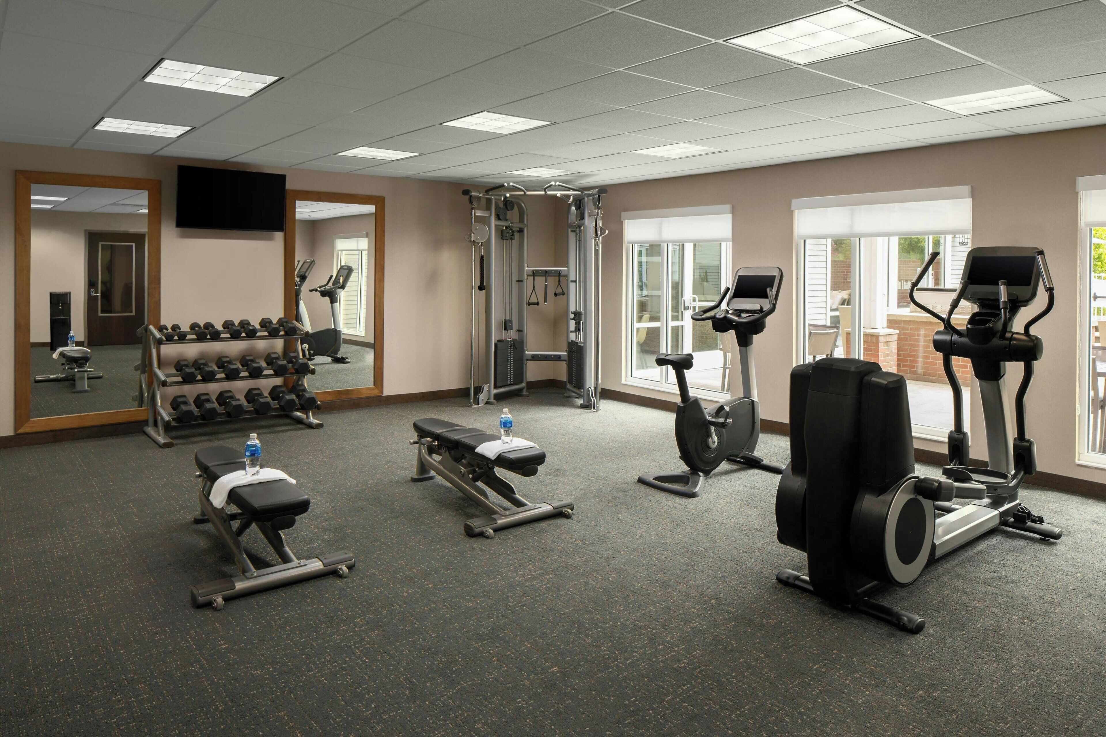 A gym with treadmills, elliptical machines, a bench press, and dumbbells.
