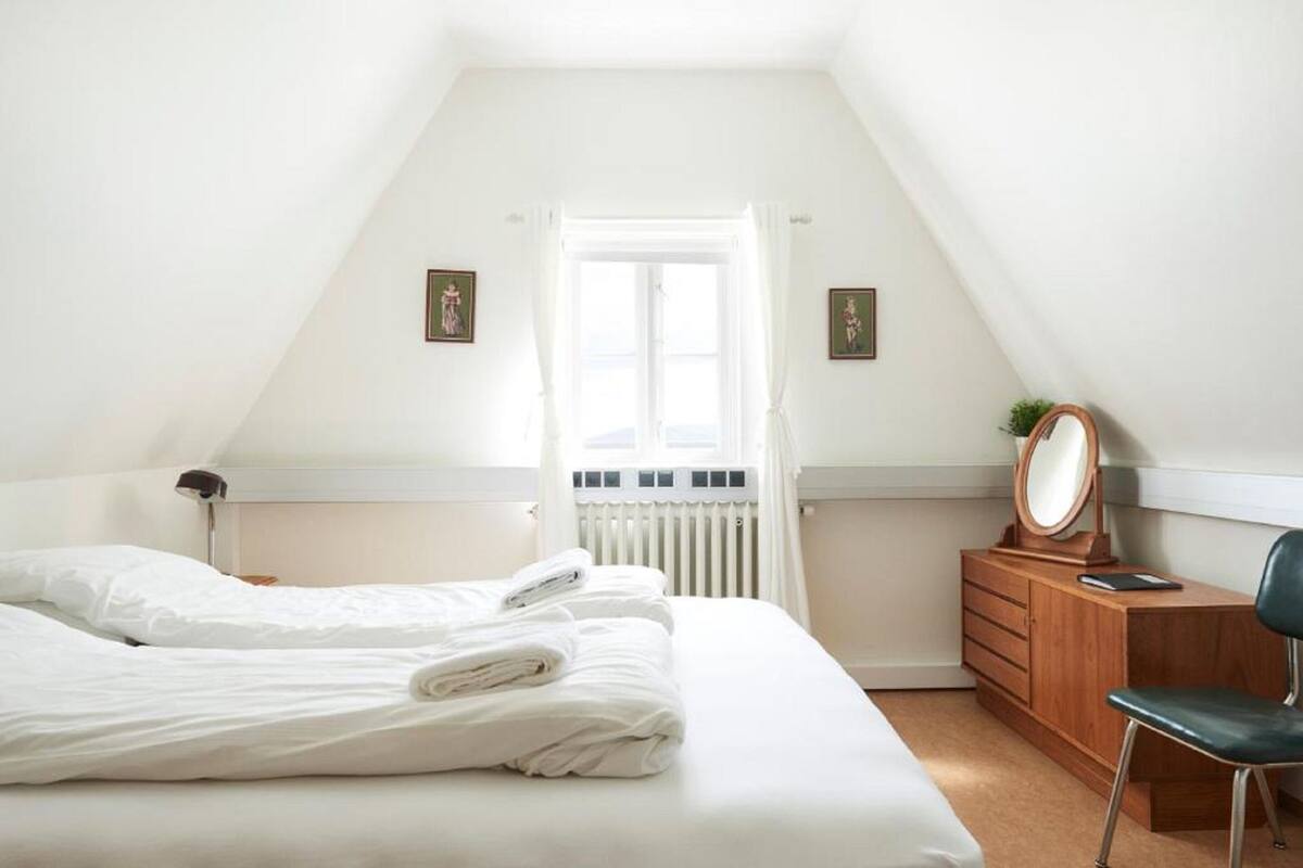 A bedroom with a bed, a dresser, a chair, and a window with curtains.