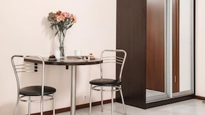 Un comedor moderno con una mesa redonda, dos sillas, un jarrón de flores y una puerta corredera.