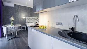Una cocina moderna con encimera gris, un lavamanos negro y una mesa de comedor redonda con un jarrón de flores.