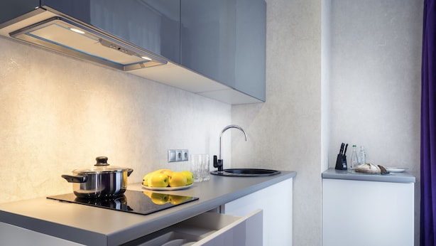 Una cocina moderna con estufa integrada, un fregadero y una encimera con una olla, limones y vasos.