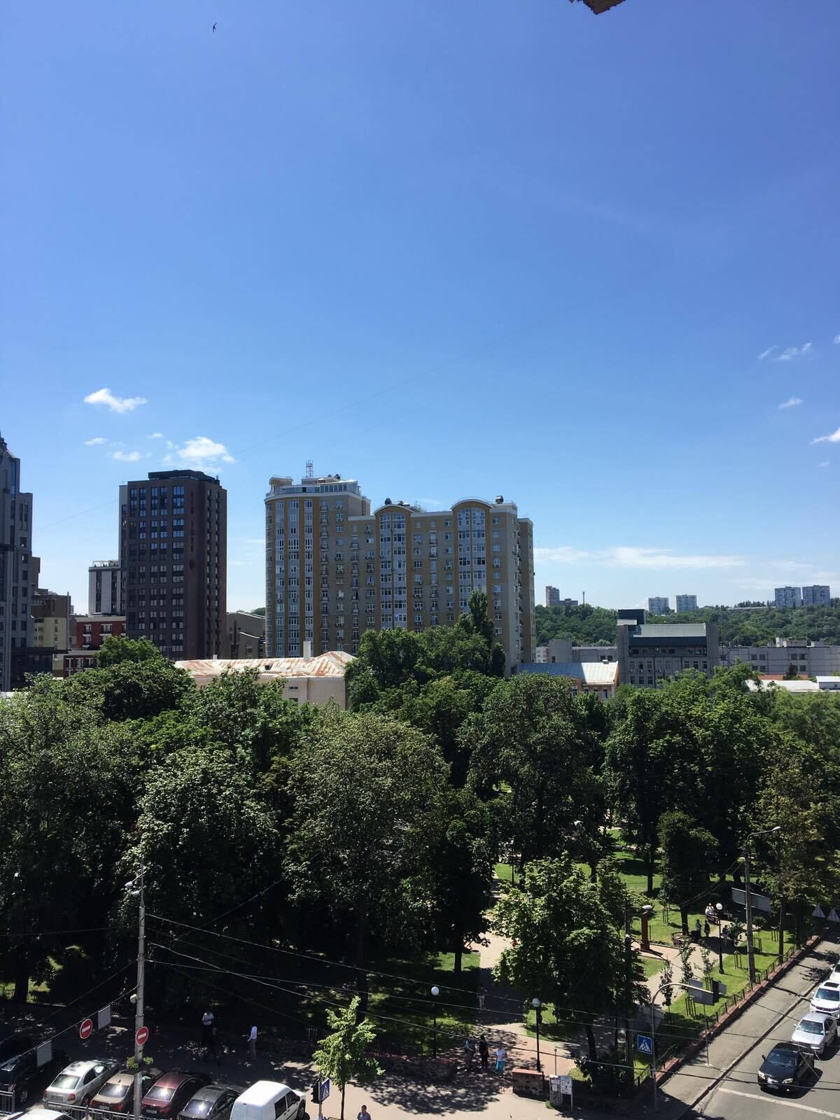 A high-rise building with multiple floors, surrounded by trees and other buildings.