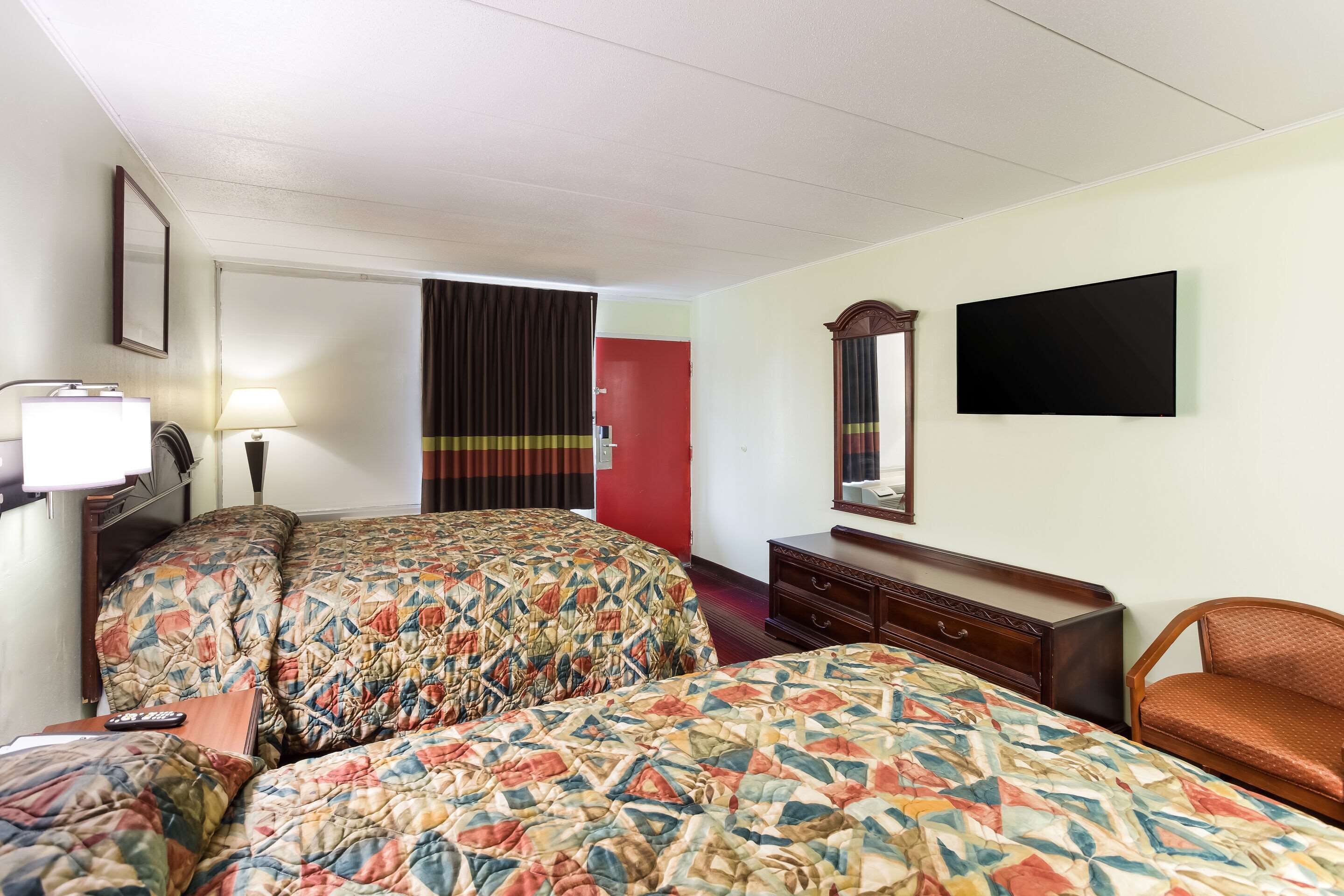 Una habitación de hotel con dos camas, un aparador, un televisor y un espejo.