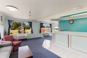 A hotel lobby with a reception desk, seating area, and large windows offering a view of the outdoors.