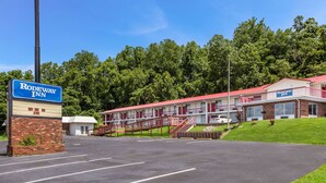 A Rodeway Inn with a brick facade, a red roof, and a parking lot. - Rodeway Inn South Point (South Point)