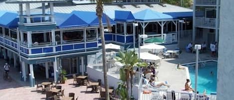 A resort with a pool area, outdoor seating, and a two-story building with blue roofs.