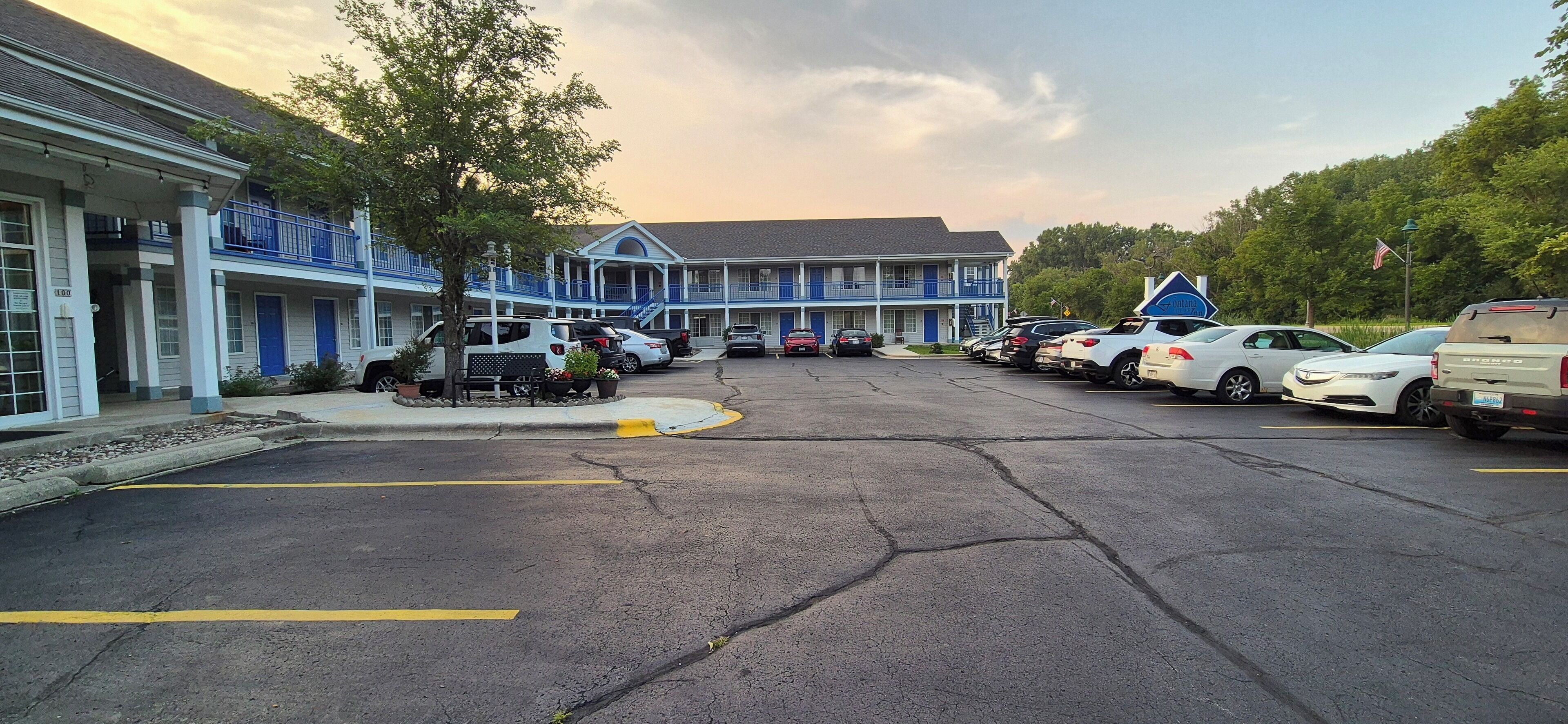 A motel with a parking lot, multiple vehicles, and a building with blue and white exterior.