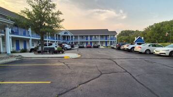 A motel with a parking lot, multiple vehicles, and a building with blue and white exterior.