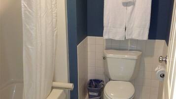 A bathroom with a toilet, a shower, and a towel rack with towels.