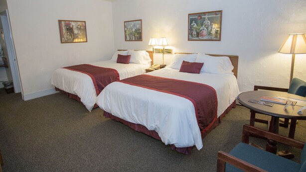 Une chambre d’hôtel avec deux lits, une table ronde et une chaise.