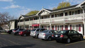 Un motel composé d’un bâtiment à deux étages, doté de nombreux balcons, et devant lequel s’étend une rangée de voitures garées.