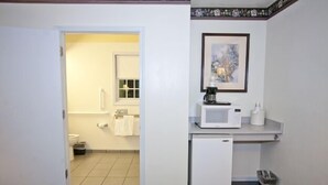 Une petite salle de bain comprenant des toilettes, un lavabo et un four à micro-ondes posé sur un petit plan de travail.