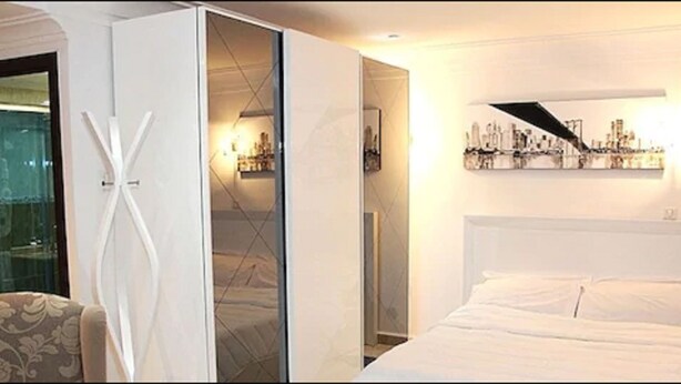 Una habitación de hotel con una cama, una silla, un armario y una obra de arte en la pared.