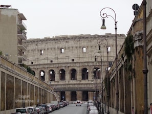 Un carrer que condueix a un edifici històric amb diverses arcades i una entrada ampla.