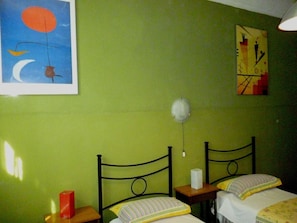 Una habitació amb dos llits, una taula de nit, un rellotge de paret i un quadre.