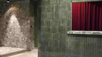 Un bagno con parete in pietra, parete rivestita di piastrelle e tenda rossa.