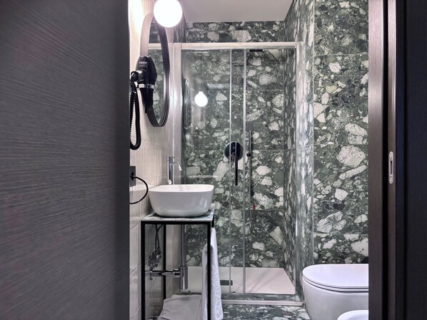 A modern bathroom with a glass-enclosed shower, a white sink, and a toilet. -  AV Hotel Milano (Milan)