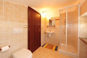 A bathroom with a toilet, sink, and glass-enclosed shower. - C'era una volta B&B (Perugia)