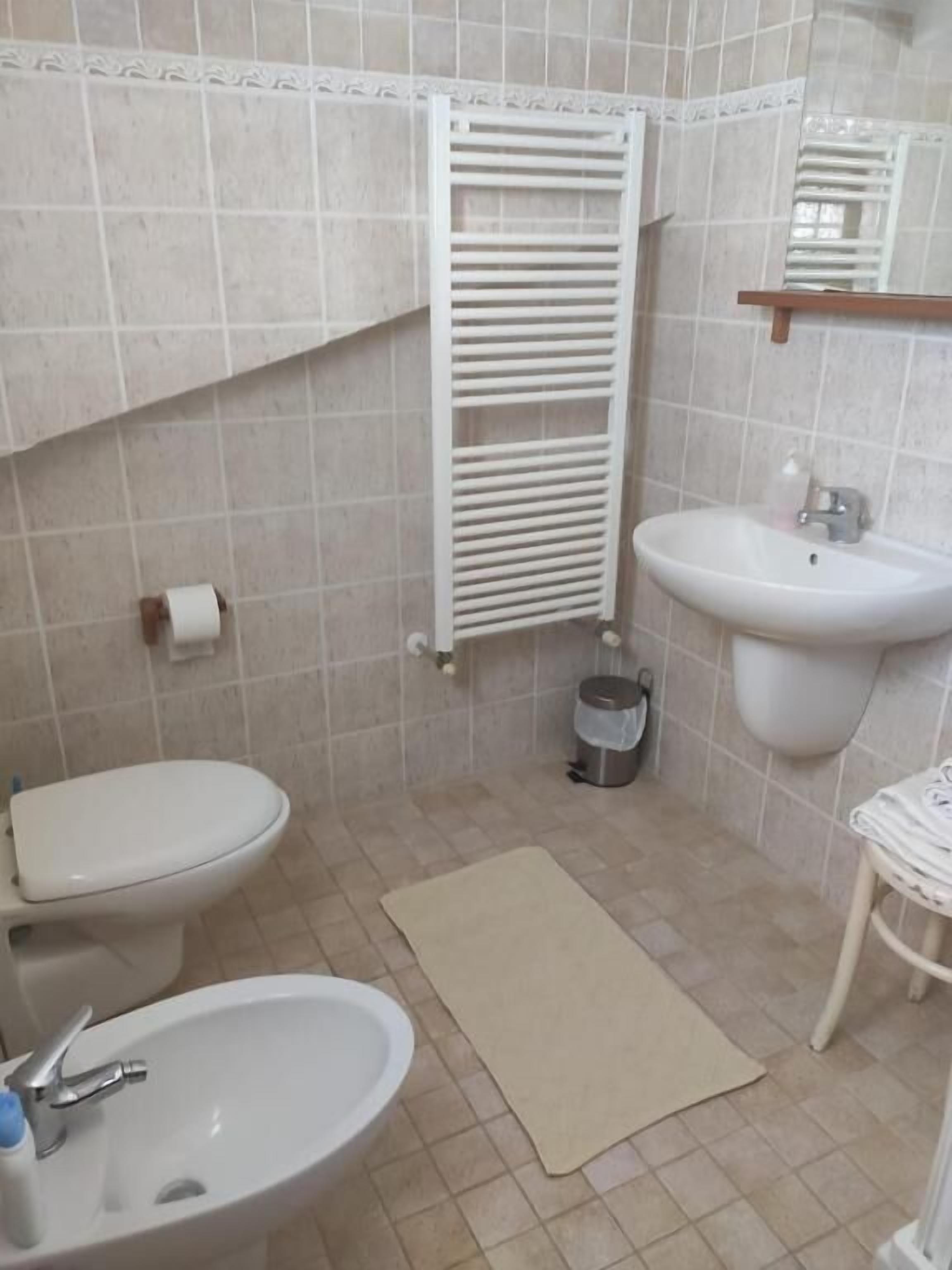 Une salle de bain équipée de toilettes, d’un lavabo et d’un porte-serviettes.