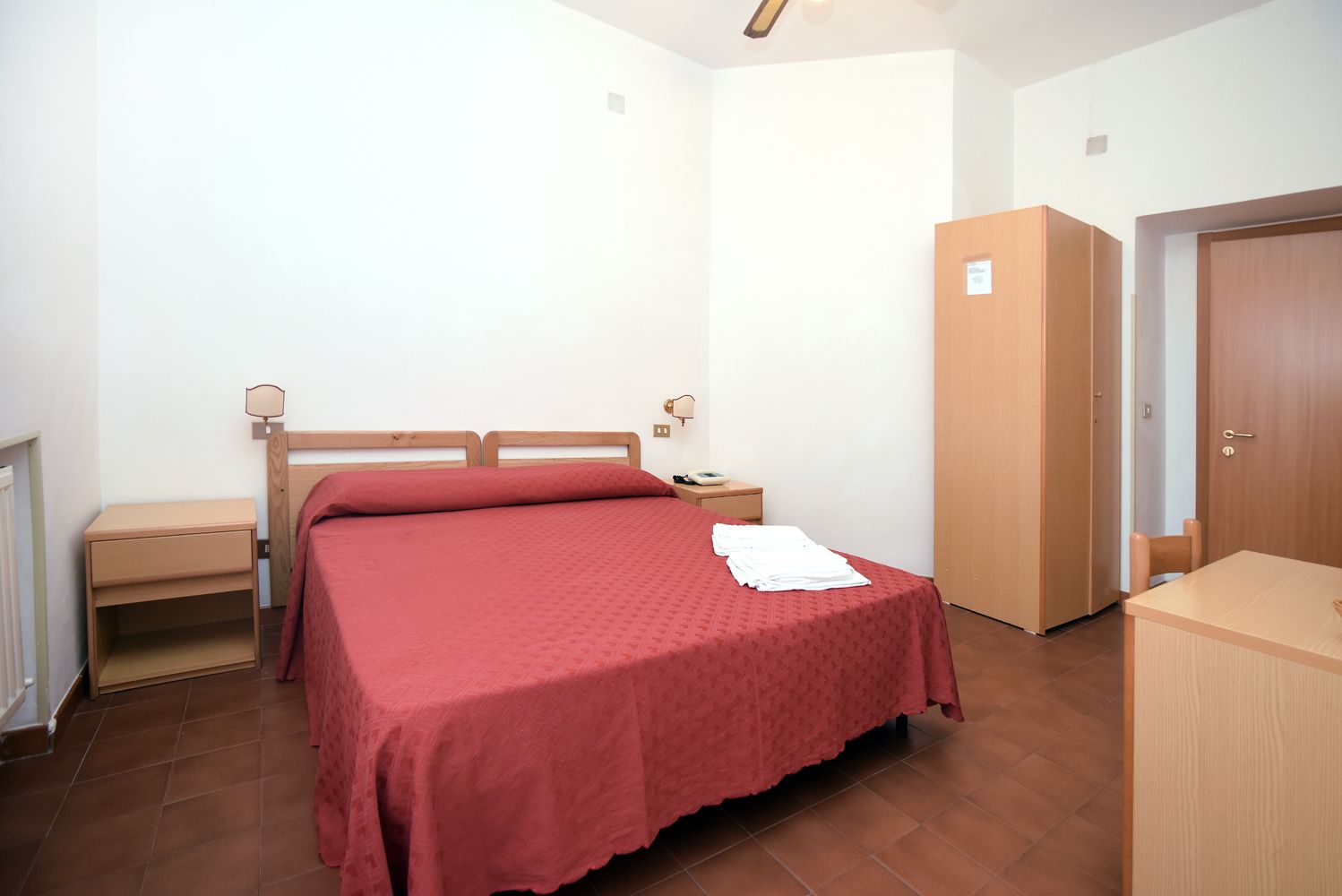 A bedroom with a bed, bedside tables, a wardrobe, and a desk.