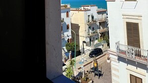 Un balcón con vista al mar y edificios cercanos.