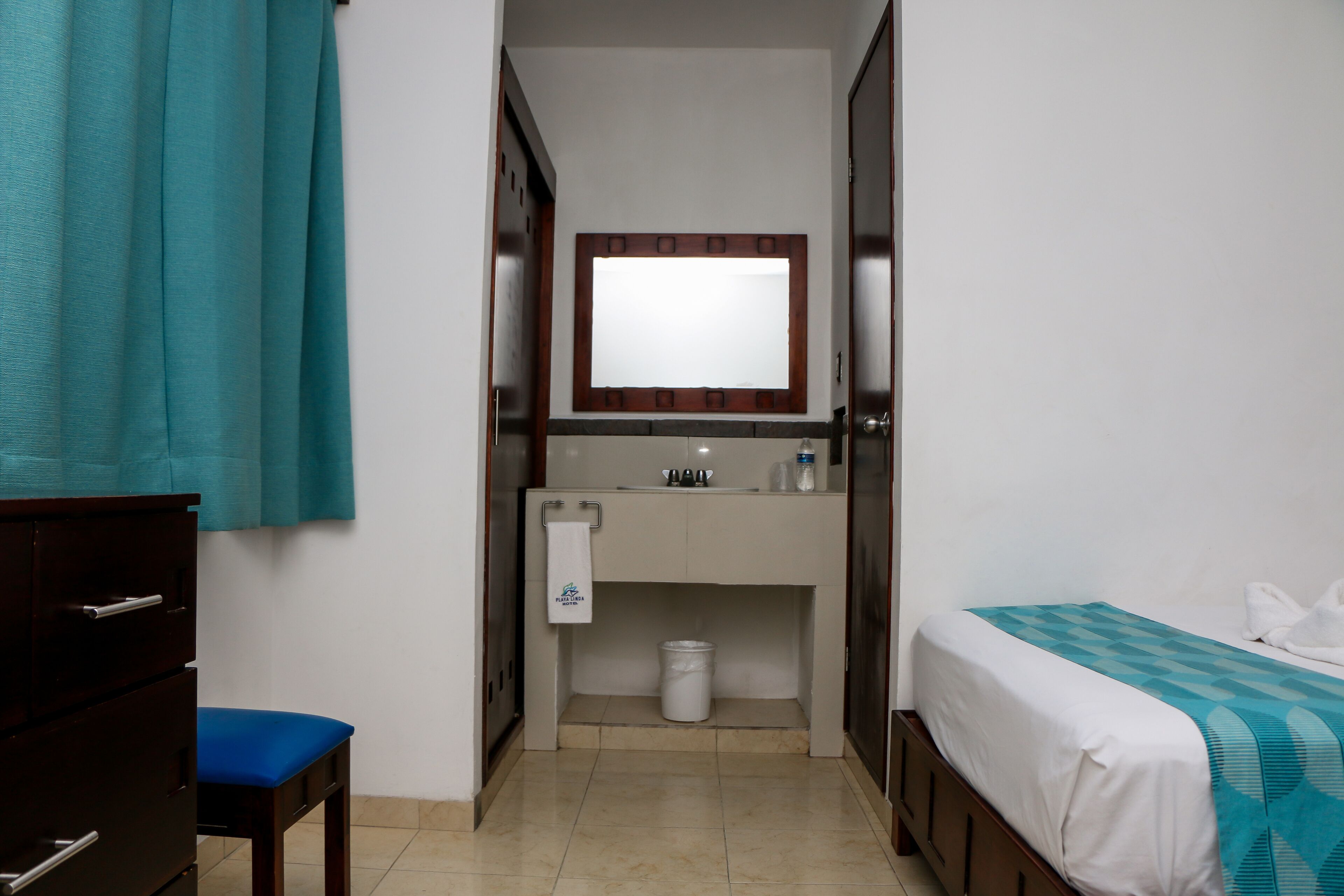 Habitació petita i ben neta amb un llit, una taula, una cadira, un vàter i un mirall.