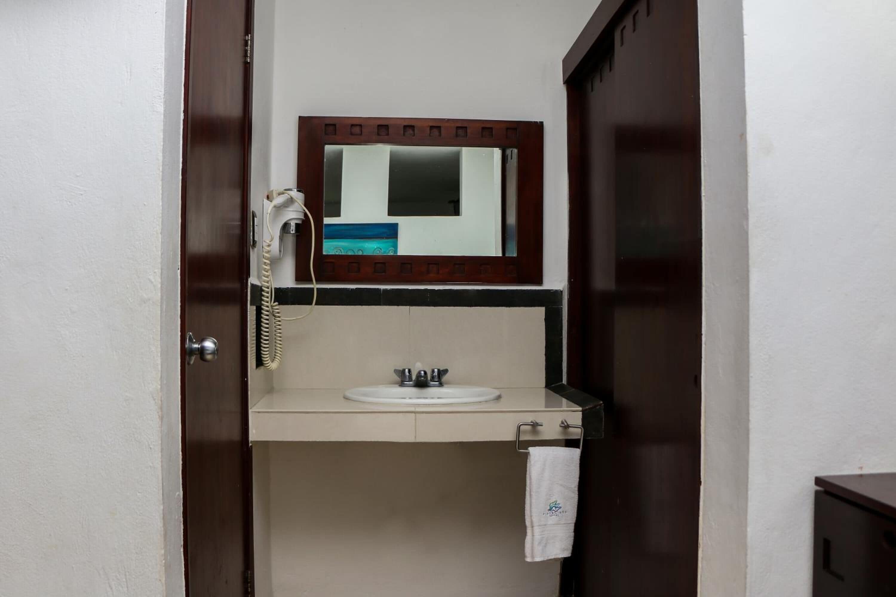 A bathroom with a wooden door, a white sink, a mirror, and a telephone.