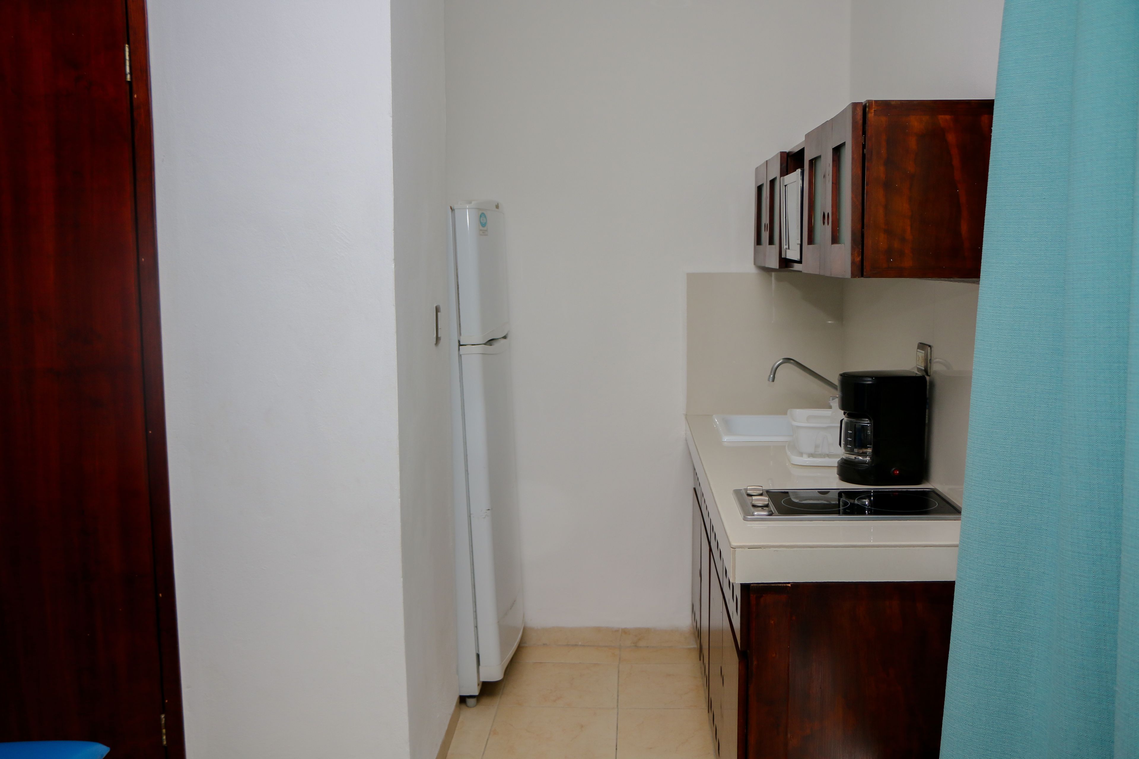 A compact kitchen with a white refrigerator, a coffee maker, and wooden cabinets.