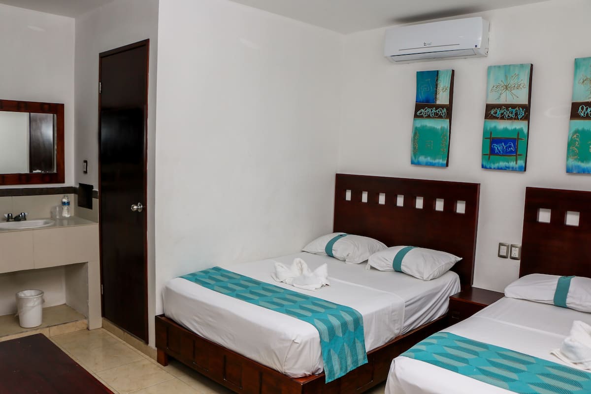 Quarto de hotel com duas camas, banheiro e obras de arte nas paredes.