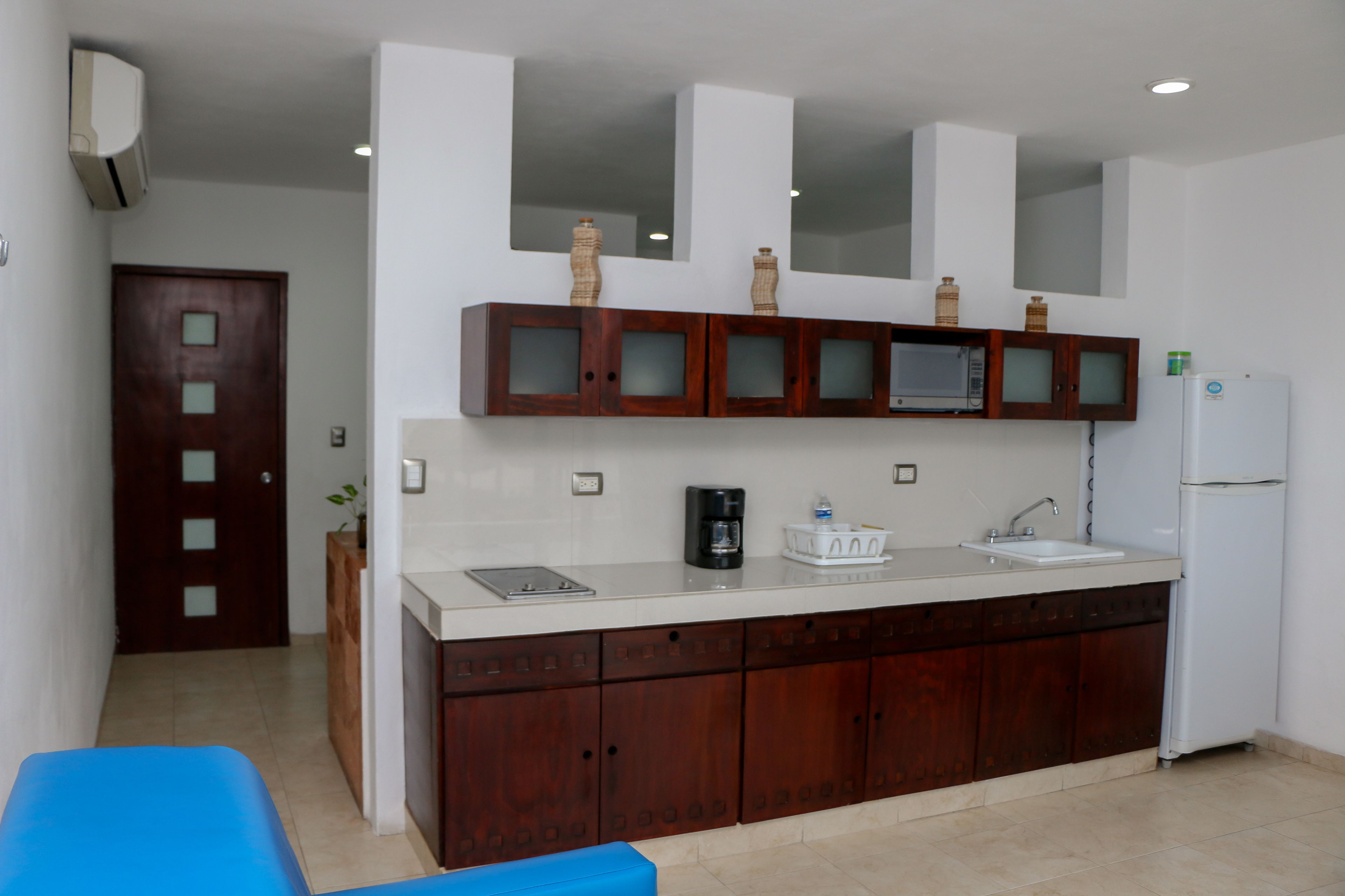 Una cocina con armarios de madera, un microondas, un refrigerador y un lavamanos.