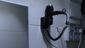 Cocina compacta equipada con microondas, hervidor de agua y secador de pelo montado en la pared.