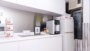 Una cocina moderna con armarios blancos, un refrigerador de acero inoxidable y una pequeña encimera con cajas y un letrero.