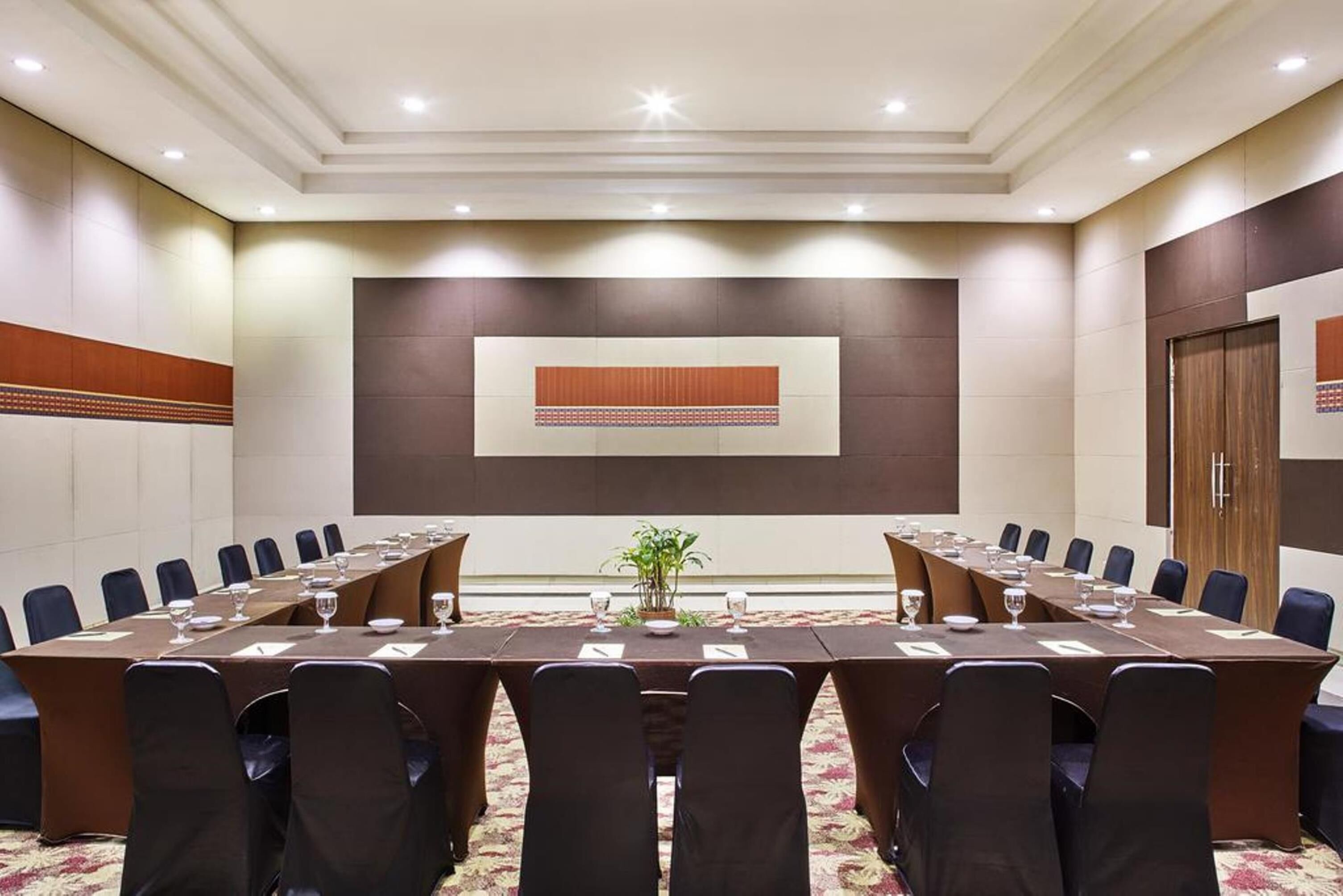 A conference room with a long table, chairs, and a plant.