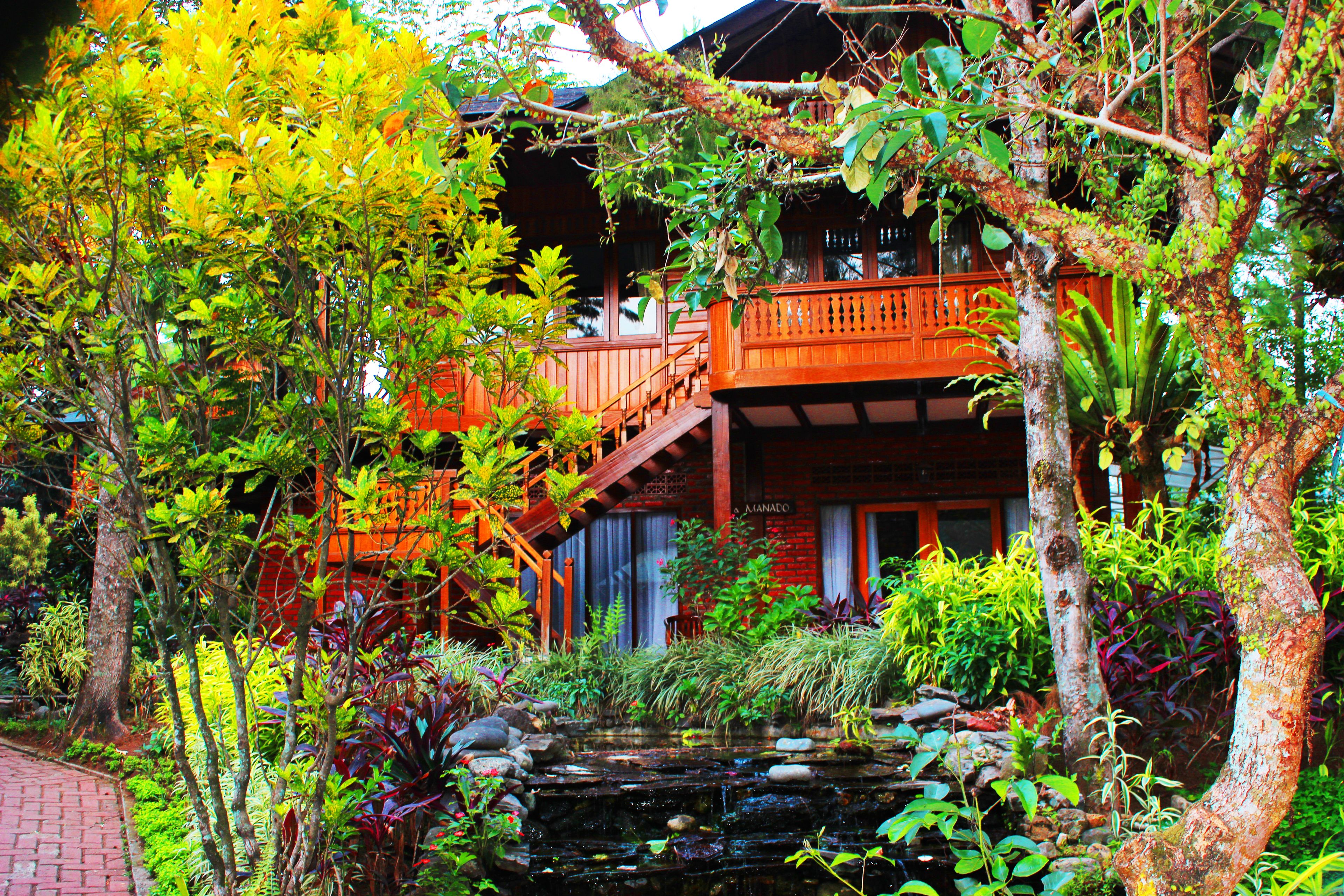 A traditional wooden building with a wooden balcony and a small pond.