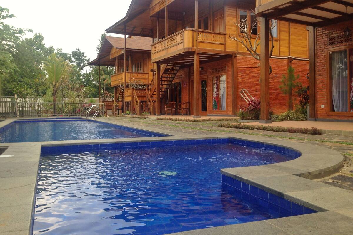 A wooden building with a swimming pool and a covered outdoor area.